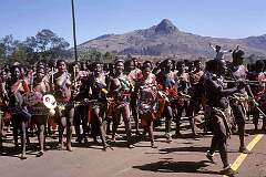 Lobamba, Eswatini, 1971 - Swazi girls, marching and singing, cross the road for the dance celebrating the end of the “uMcwasho”, when they were subject to strict laws.