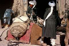 Keeping the camel seated by placing a foot on his leg, it was offloaded.