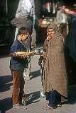 A boy selling bread and a woman on the street in Mashhad.