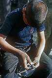 A boy, engraving a silver bowl in a workshop in Mashhad.